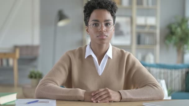 Jovem menina africana sorrindo e sentada em sua mesa de trabalho — Vídeo de Stock