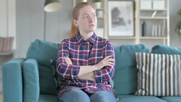 Ung kvinna sitter på soffan och tänker — Stockvideo