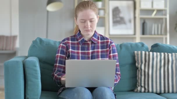 Jovem mulher sentada no sofá e usando laptop — Vídeo de Stock