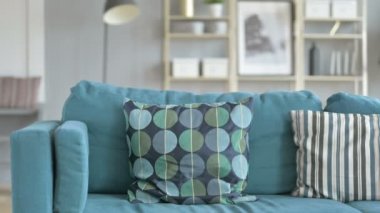 Kanepede oturan ve dizüstü bilgisayarda çalışan genç bir kadın.