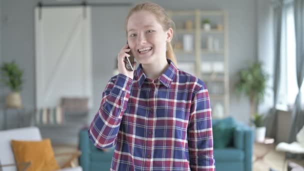 Молодая женщина стоит и разговаривает по смартфону — стоковое видео