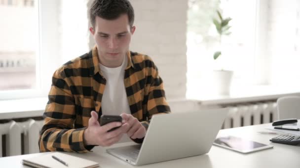 Hombre joven casual usando Smartphone en el trabajo — Vídeos de Stock