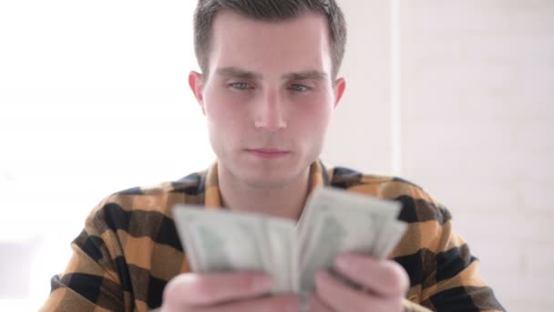 Напряженный молодой человек считает долларовую бумажную валюту — стоковое видео