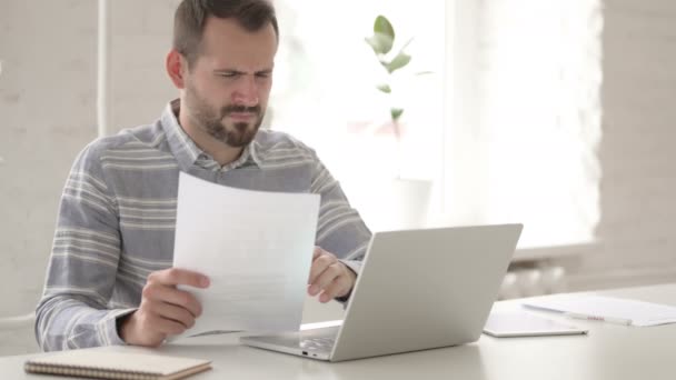 Joven adulto tenso leyendo documentos de la oficina — Vídeo de stock