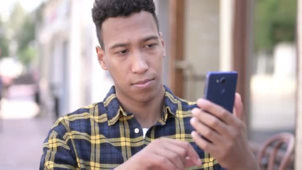 Νέος Αφρικανός άνθρωπος χρησιμοποιώντας smartphone, υπαίθριος — Αρχείο Βίντεο