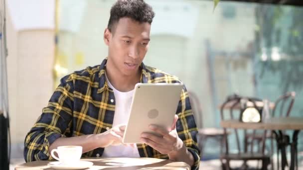 タブレット、屋外カフェでの成功に興奮する若いアフリカの男性を獲得 — ストック動画