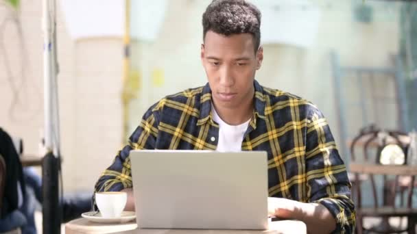 Młody afrykański człowiek z bólem szyi za pomocą laptopa, outdoor Cafe — Wideo stockowe