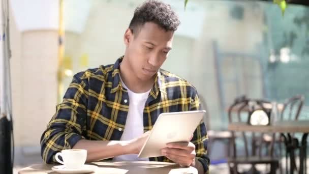 Молодой африканский человек с помощью планшета, кафе на открытом воздухе — стоковое видео