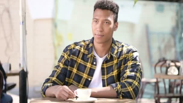 Avkopplande ung afrikansk man dricka kaffe, utomhus café — Stockvideo