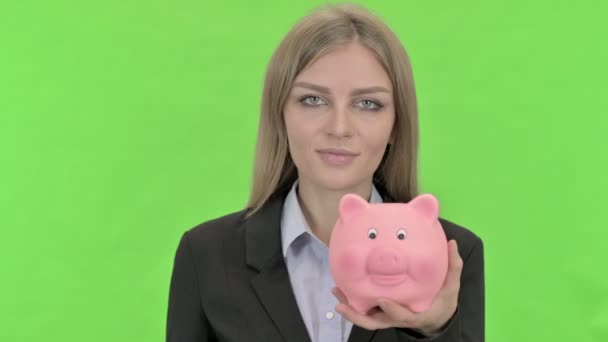 Mujer de negocios Insertando Moneda en Piggy Bank contra Chroma Key — Vídeo de stock