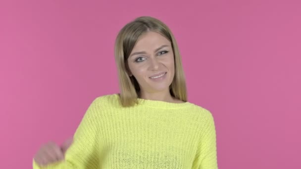 Mooie jonge meid toont duimen naar beneden, roze achtergrond — Stockvideo