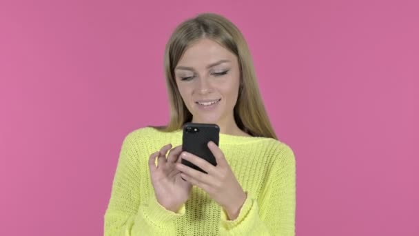 Chica joven feliz usando Smartphone, Fondo rosa — Vídeos de Stock