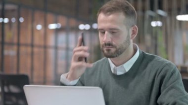 Yakından çekilen yakışıklı adam cep telefonuyla konuşuyor.