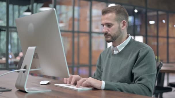 Jongeman denken tijdens het werken op de computer — Stockvideo