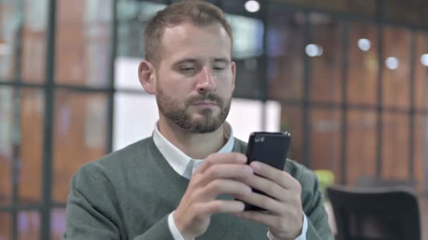 Портрет молодого человека, прокручивающегося по сотовому телефону — стоковое видео