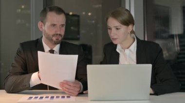 Geceleri Belgeler ve Laptop üzerinde çalışan İşletme Yöneticileri