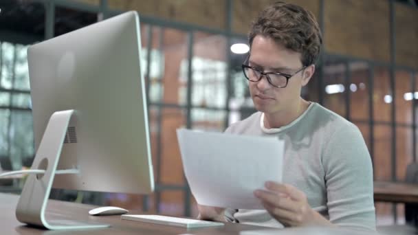 Красивий хлопець працює над документом і комп'ютером — стокове відео