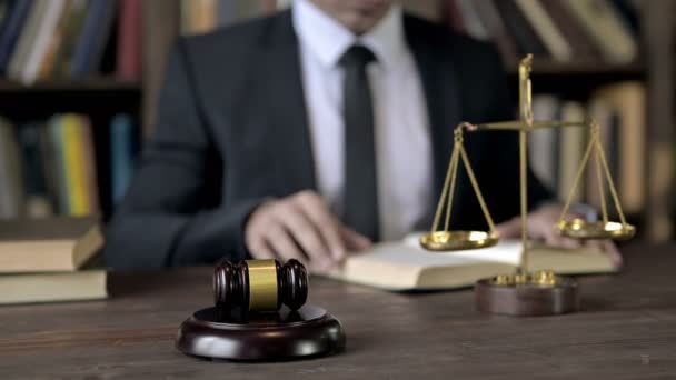 Närbild Shoot of Judge Hand Läsa bok i oskärpa med Gavel och skala — Stockvideo