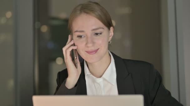 Primer plano de la empresaria hablando por teléfono celular en el escritorio de la oficina por la noche — Vídeos de Stock