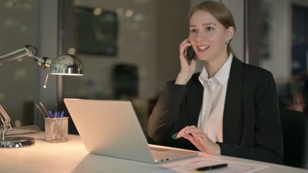 Vrolijke zakenvrouw aan het praten op mobiele telefoon in Office 's nachts — Stockvideo
