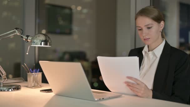 Preciosa empresaria leyendo el documento en el escritorio de la oficina por la noche — Vídeos de Stock