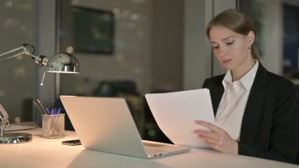 Femme d'affaires ambitieuse lisant un document sur le bureau la nuit — Video