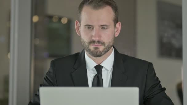 Primer plano del hombre de negocios guapo que trabaja en el ordenador portátil por la noche — Vídeo de stock