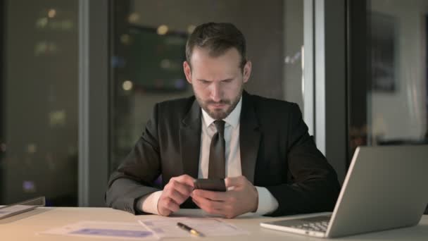 Geschokt Zakenman Scrollen op mobiele telefoon 's nachts — Stockvideo