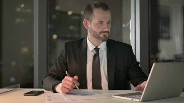 Homme d'affaires intelligent travaillant sur ordinateur portable et document la nuit — Video