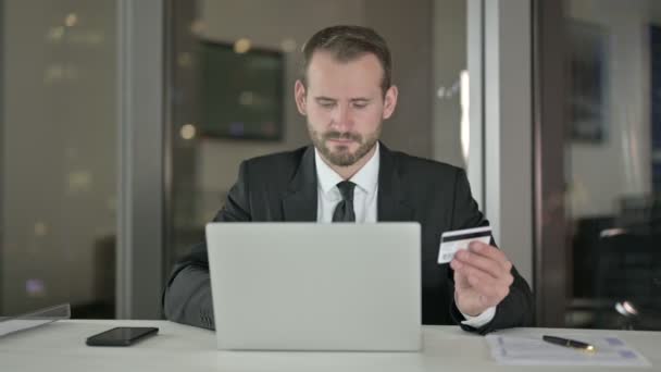 Bonito empresário usando cartão de crédito no laptop à noite — Vídeo de Stock