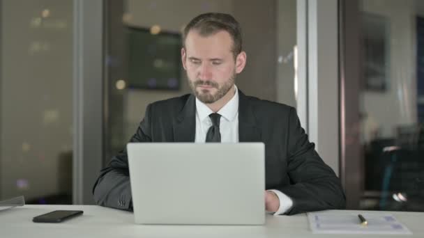 Hombre de negocios guapo trabajando en el ordenador portátil por la noche — Vídeos de Stock