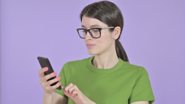 Młoda kobieta za pomocą telefonu komórkowego na różowym tle — Wideo stockowe