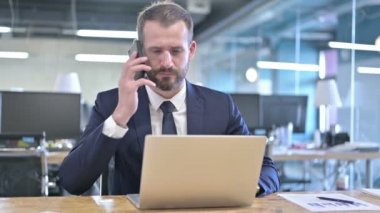Hırslı genç iş adamı Smartphone 'da konuşuyor.
