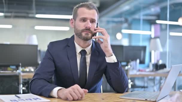 Empresário alegre conversando no smartphone no escritório — Vídeo de Stock