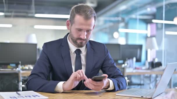 Jovem empresário comemorando no smartphone com punho — Vídeo de Stock