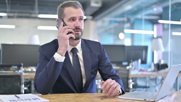 Jungunternehmer spricht im Büro über Smartphone — Stockvideo