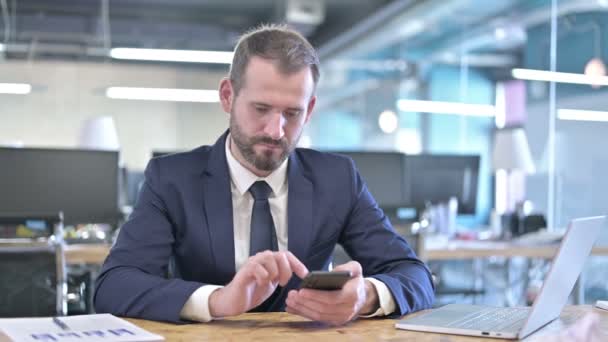 Concentrarsi giovane imprenditore utilizzando Smartphone in ufficio — Video Stock
