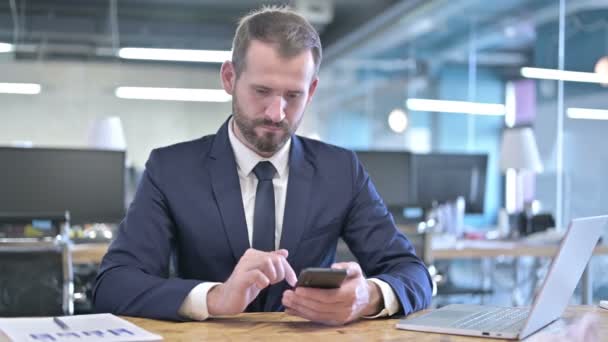 Jovem empresário usando Smartphone na mesa de escritório — Vídeo de Stock