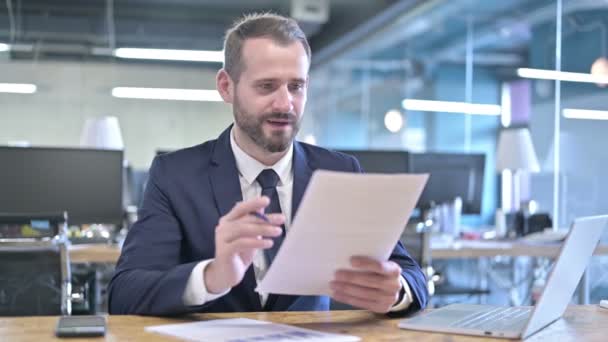 Успешный молодой бизнесмен празднует и проверяет документы — стоковое видео