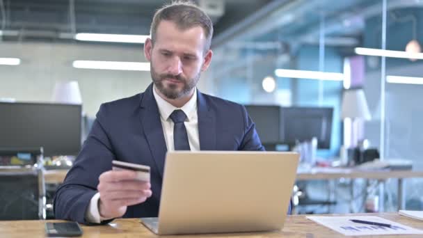 Молодий бізнесмен використовує кредитну картку на ноутбуці — стокове відео
