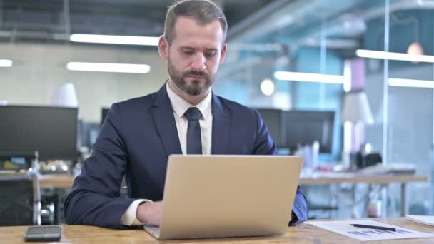 Mladý podnikatel pracující na notebooku na kancelářském stole — Stock video