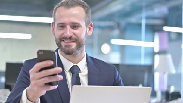 Portrait of Cheerful Businessman using Smartphone in Office — Stockvideo