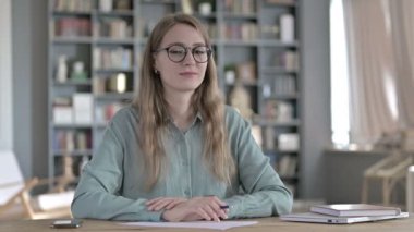 Ofiste otururken kameraya bakan hırslı kadın.