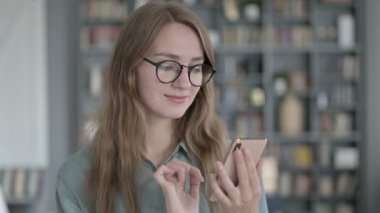 Ofiste akıllı telefon kullanan genç bir kadının portresi