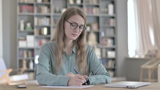 Seriöse Frau schreibt im Büro auf Papier — Stockvideo