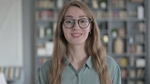Porträt einer fröhlichen Frau, die im Büro lächelt und in die Kamera winkt — Stockvideo