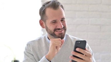 Genç Adam Smartphone 'da okurken Sevinç Duyuyor