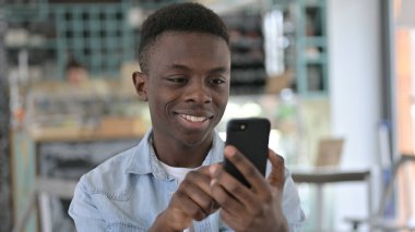 Akıllı telefon kullanan neşeli Afrikalı bir gencin portresi