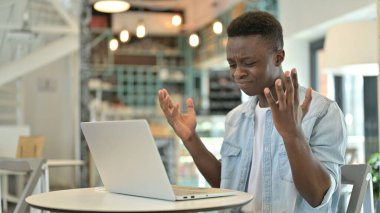 Kafe 'de dizüstü bilgisayardan Loss' a tepki veren üzgün bir Afrikalı.