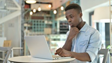 Kafe 'de laptopta düşünen ve çalışan dalgın bir Afrikalı.